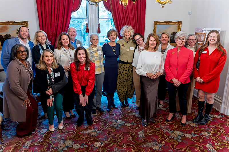 A group of people standing and smiling for the camera inside an older well-decorated home.